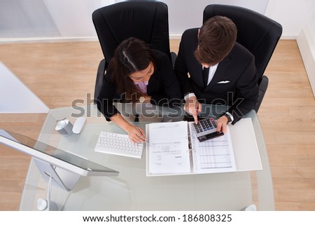 Business colleagues calculating tax together at desk in office
