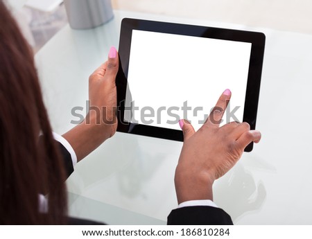 Cropped image of businesswoman\'s hands holding digital tablet at desk in office