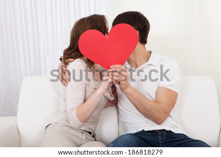 Affectionate couple relaxing on a sofa with the mans arm around his wifes shoulders