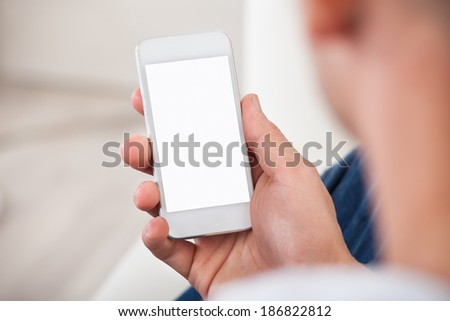 Over the shoulder view of the blank screen on a smartphone or mobile phone held in a mans hand