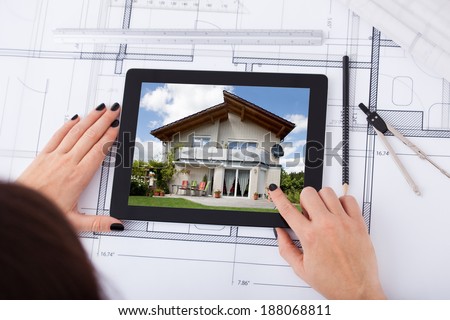 High angle view of architect woman with digital tablet and blueprint at desk in office