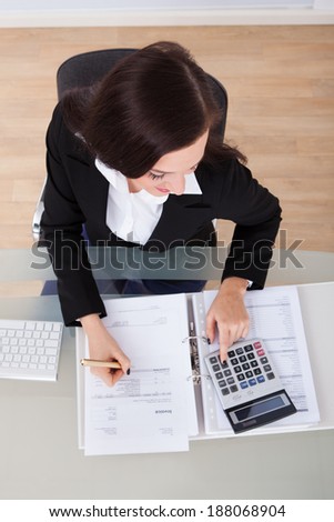 High angle view of businesswoman calculating tax at desk in office