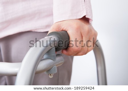 Closeup of senior woman with walking frame against white background