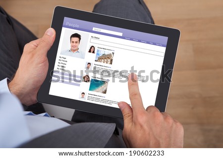 Midsection of businessman surfing social networking site on digital tablet in office