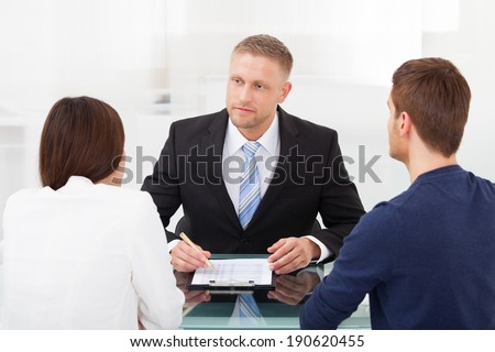 Rear view of young couple consulting financial advisor at office desk