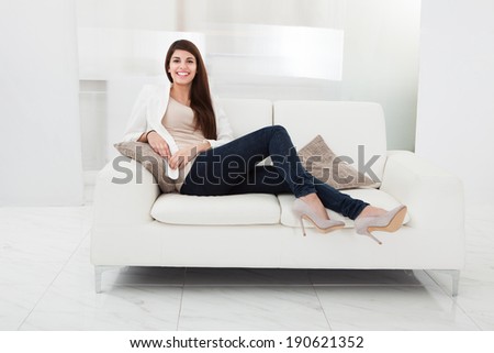 Casual woman in jeans sitting on a couch in her living room