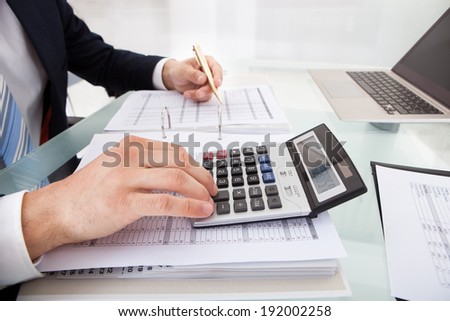 Cropped image of businessman calculating expense at desk in office
