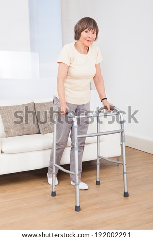Full length portrait of senior woman using walking frame at nursing home