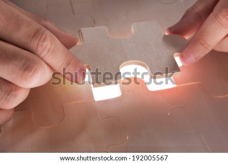 Closeup of businessman fixing jigsaw pieces at desk