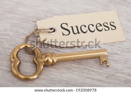 Golden key with success tag on wooden table