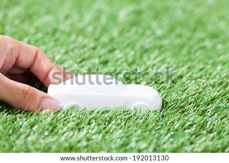 Closeup of hand holding car model in green field