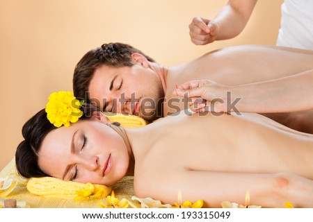 Relaxed young couple receiving acupuncture treatment at beauty spa