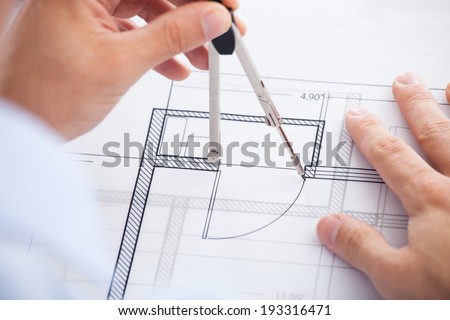 Cropped image of male architect using divider on blueprint in office