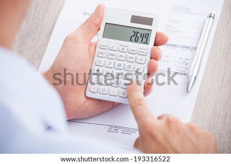 Cropped image of businessman calculating invoice at desk