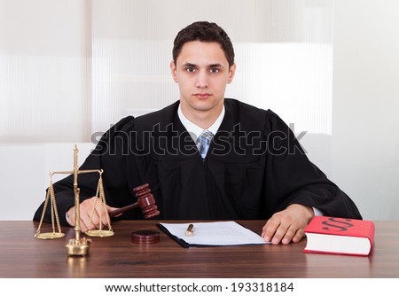 Portrait of confident male judge sitting at table in courtroom