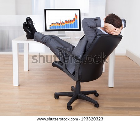 Full length of businessman with feetup relaxing at computer desk in office
