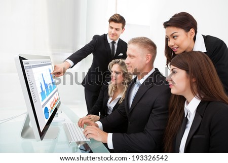 Group of businesspeople using desktop PC together in office