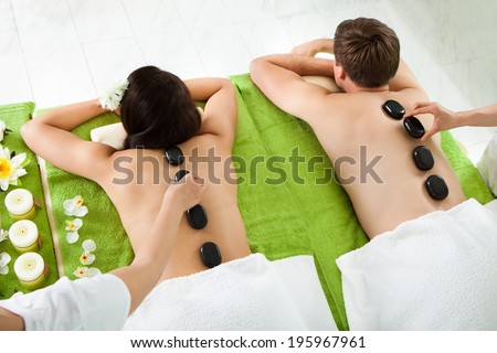 High angle view of young couple receiving hot stone massage at beauty spa