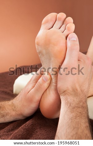 Closeup of male therapist giving foot massage to female customer at beauty spa