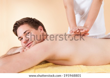 Young man receiving back massaging in spa