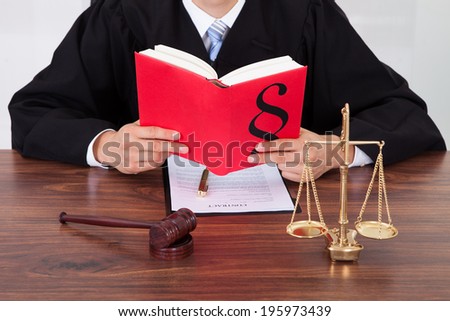 Midsection of male judge reading book at table in courtroom