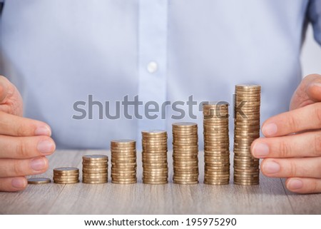 Midsection of businessman\'s hand protecting euro coins at office desk