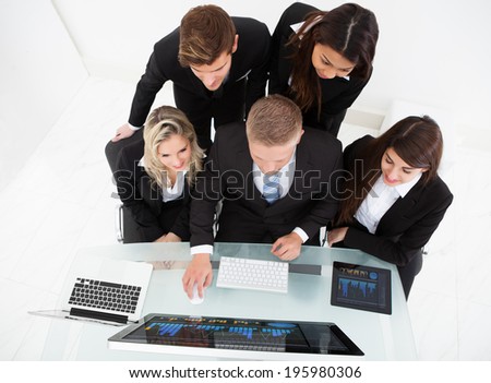 High angle view of businesspeople using desktop PC together at desk in office