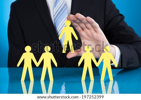 Midsection of businessman holding paper people representing recruitment against black background