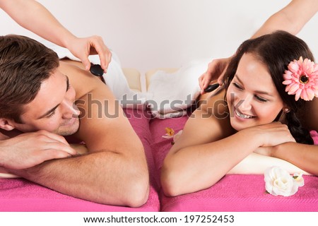Portrait of happy young couple enjoying hot stone massage at beauty spa