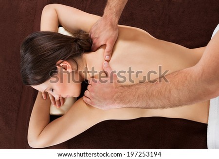 Directly above shot of young woman receiving shoulder massage at beauty spa
