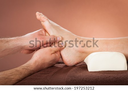 Cropped image of male therapist giving foot massage to female customer at beauty spa