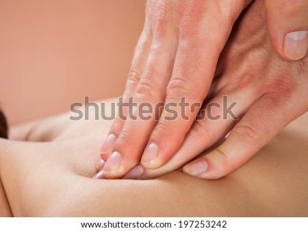 Closeup of male therapist massaging female customer\'s back at beauty spa