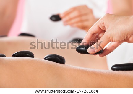 Closeup of young couple receiving hot stone therapy at beauty spa