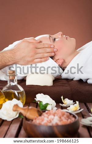 Side view of relaxed young woman receiving head massage at beauty spa