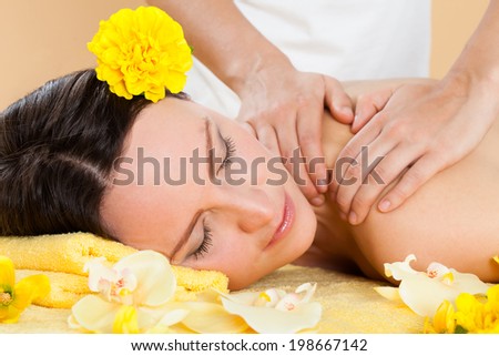 Portrait of smiling young woman receiving shoulder massaging in spa