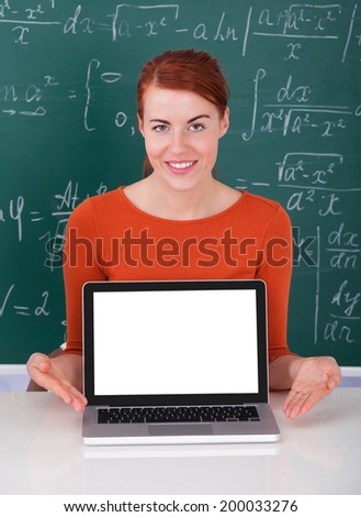 Portrait of beautiful university student presenting laptop in classroom