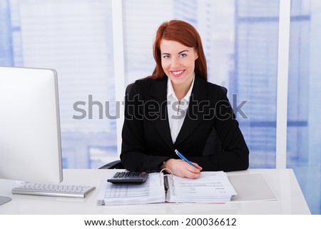 Portrait of confident businesswoman calculating tax at office tax