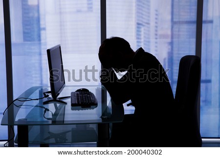 Side view of tired young businessman sleeping at computer desk in office