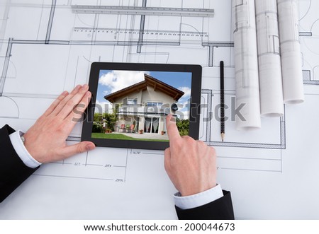 Cropped image of male architect using digital tablet on blueprint in office