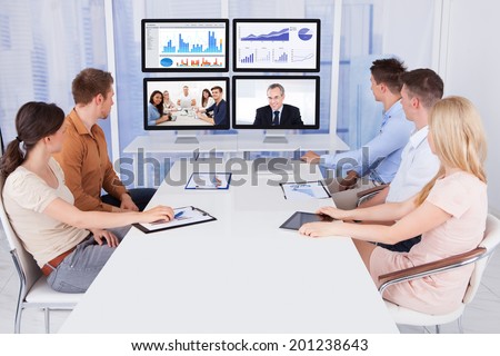Young business people looking at computer monitors in conference room