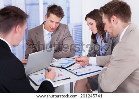 Group of young business people discussing at table in office