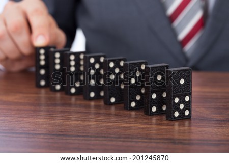 Midsection of businessman playing domino on desk