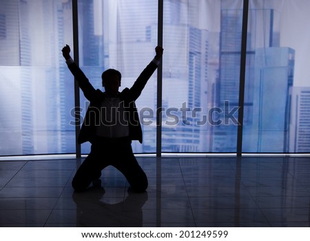 Full length rear view of businessman sitting arms outstretched by office window