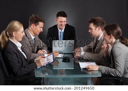 business people discussing in conference meeting at desk against black background