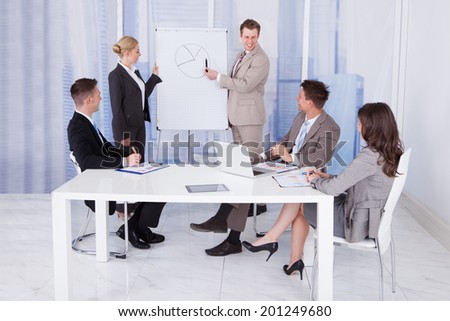 Young businessman giving presentation to colleagues in conference room
