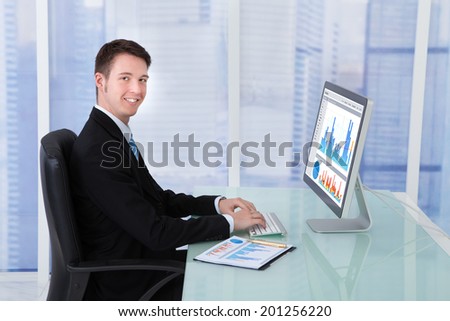 Side view of concentrated businessman working on computer at desk in office