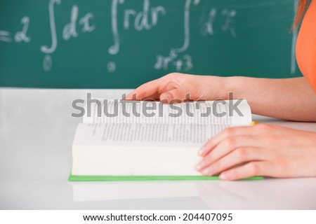 Cropped image of young university student reading book in classroom