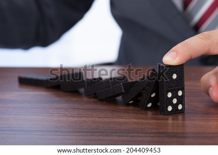 Midsection of businessman playing domino on desk