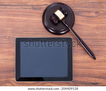 Closeup of judge mallet on block by digital tablet in courtroom