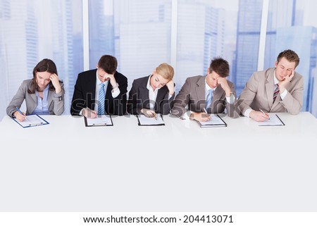 Group of tired corporate personnel officers at table in office